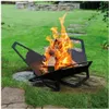 A black metal fire pit with burning wood is placed on a stone and grass area in a garden. Produktbild-Vorschau