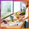 A woman is preparing food in a kitchen, with vacuum sealing rolls in the foreground. Podgląd zdjęcia produktu