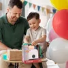A father and son are opening a gift, which is a toy toaster, at a birthday party. Anteprima dell’immagine prodotto