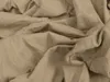 A close-up view of crumpled beige fabric. Produktbild-Vorschau