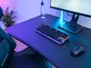 A gaming setup with a keyboard, mouse, and monitor, illuminated by colorful LED lights. Produktbild-Vorschau