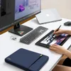 A desk setup with a laptop, monitor, keyboard, drawing tablet, and a laptop sleeve. Produktbild-Vorschau