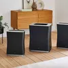 Three black air purifiers are arranged on a wooden floor in front of a wooden dresser. A plant is visible to the left. Podgląd zdjęcia produktu