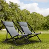 Two grey folding lounge chairs are set up on a grassy lawn with trees and a blue sky in the background. Voir les images du produit