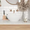 A white oval basin sink on a speckled countertop with brass faucets and decorative elements. Anteprima dell’immagine prodotto