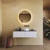 A modern bathroom vanity with a round illuminated mirror, sink, and storage. Produktbild-Vorschau