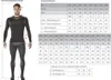 A man wearing a black and dark gray long-sleeved shirt and pants, standing next to a size chart for trousers/overalls. Anteprima dell’immagine prodotto