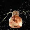 A perfume bottle with liquid splashing around it. Voir les images du produit