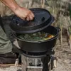 A person is cooking in a Dutch oven over a rocket stove outdoors. Produktbild-Vorschau