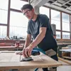 A man is sanding a wooden surface in a workshop. Anteprima dell’immagine prodotto