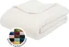 A folded white blanket is shown on a white background, with a circular swatch of color samples and text overlay in the lower left corner. Produktbild-Vorschau