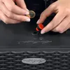 A person's hands are shown inserting a red plug into a black planter. Produktbild-Vorschau