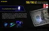 A Nitecore TIKI keychain light is shown demonstrating its counterfeit bill detection feature on a US $100 bill. Podgląd zdjęcia produktu