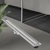 A linear shower drain is shown in the foreground, with a tiled shower area in the background. Produktbild-Vorschau