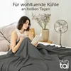 A woman is reading a book in bed, covered by a dark gray blanket, with a fan and flowers in the background. Anteprima dell’immagine prodotto