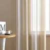 A close-up of sheer curtains hanging in front of a window, with a small table holding a decorative 'M' and a mug to the left. Produktbild-Vorschau