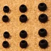 A close-up view of multiple black earbud tips arranged on a textured brown surface. Náhľad obrázku produktu