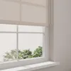 A close-up view of a roller blind on a window, with trees visible outside. Produktbild-Vorschau