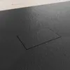 A close-up view of a black shower tray with a rectangular drain cover. Produktbild-Vorschau