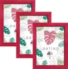 Three red picture frames are arranged in a staggered formation against a white background, showcasing a tropical leaf pattern within each frame. Produktbild-Vorschau