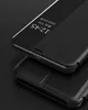 A close-up view of a black leather phone case with a transparent window showing the time and date. Produktbild-Vorschau