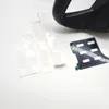 A black steering wheel accessory and some white stickers are laid out on a white surface. Produktbild-Vorschau