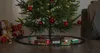 A Christmas train set is placed around the base of a decorated Christmas tree, with gifts piled to the side. Podgląd zdjęcia produktu