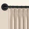 A close-up view of a black metal curtain rod with rings and beige curtains. Produktbild-Vorschau