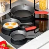A set of cast iron frying pans of different sizes on a black stovetop. Produktbild-Vorschau