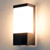 A modern, rectangular outdoor wall light with a black base and a frosted white light panel, mounted on a wall. Náhľad obrázku produktu