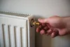 A hand is turning the valve on a radiator. Produktbild-Vorschau