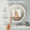 A bathroom scene with a round LED mirror, a woman's reflection, and sink accessories. Produktbild-Vorschau