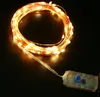 A coiled string of warm white LED lights with a copper wire and a small battery pack with a blue button. Produktbild-Vorschau