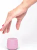 A hand reaching down towards a small pink speaker. Náhľad obrázku produktu