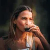 A woman is drinking from a small cup. Produktbild-Vorschau