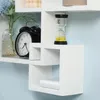 A white modular shelving unit with various decorative items placed on it, including a clock, a vase with flowers, an hourglass, and a power bank. Voir les images du produit
