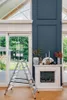 A ladder is placed in front of a fireplace and large windows overlooking a garden. Anteprima dell’immagine prodotto