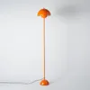 A tall, orange floor lamp with a mushroom-shaped shade stands against a white background. Podgląd zdjęcia produktu
