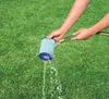 Hands holding a blue filter under a stream of water from a hose, with green grass in the background. Produktbild-Vorschau