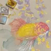 A close-up of watercolor paints and a painting of a goldfish. Voir les images du produit