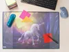 A desk mat with a unicorn design, placed on a desk with a keyboard, mouse, stapler, and sticky notes. Náhľad obrázku produktu