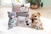 A collection of plush animal pillows and stuffed toys arranged on a white rug, with a potted plant in the background. Produktbild-Vorschau