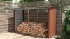 A wooden log storage shed filled with firewood, set against a wooden fence and greenery. Náhled obrázku produktu