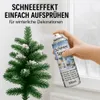 A hand spraying artificial snow onto a small artificial Christmas tree. Produktbild-Vorschau