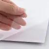 Transparente Schutzfolie wird von einer Hand abgezogen, darunter eine weiße Oberfläche Voir les images du produit