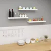 A kitchen scene with shelves displaying various items, including wine bottles, glassware, jars, and decorative objects, above a tiled backsplash and a wooden countertop. Produktbild-Vorschau