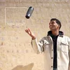 A man is juggling a travel mug in front of a textured wall. Náhľad obrázku produktu