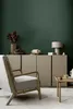 A living room scene with a sofa, armchair, and a cabinet against a dark green wall. Produktbild-Vorschau