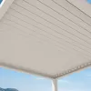 A close-up view of the underside of a white pergola roof with a slatted design, against a bright blue sky. Náhled obrázku produktu