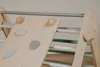 A close-up view of a wooden climbing triangle with pastel-colored rungs and climbing holds. Voir les images du produit